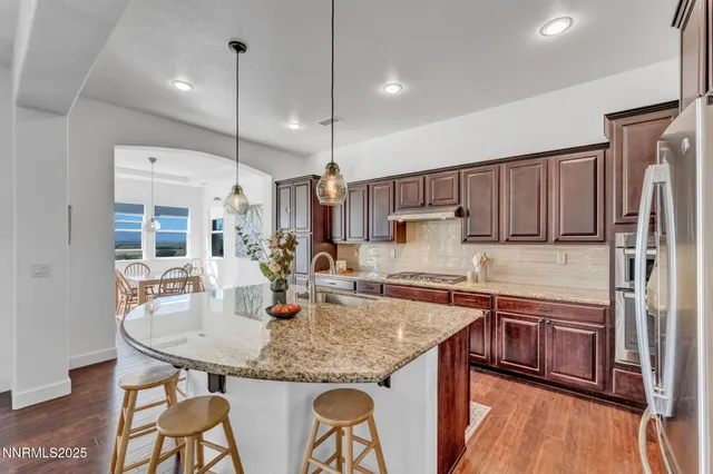 a kitchen with stainless steel appliances granite countertop a kitchen island a stove a table and chairs