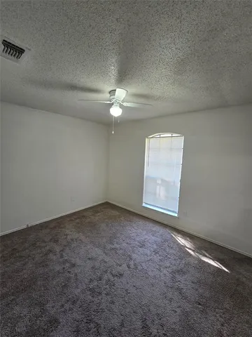 an empty room with a chandelier fan and windows