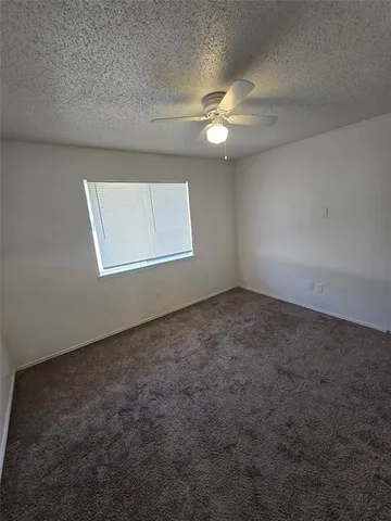 an empty room with a chandelier fan and windows