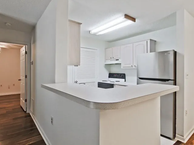 a kitchen with kitchen island a sink a stove a refrigerator and white cabinets