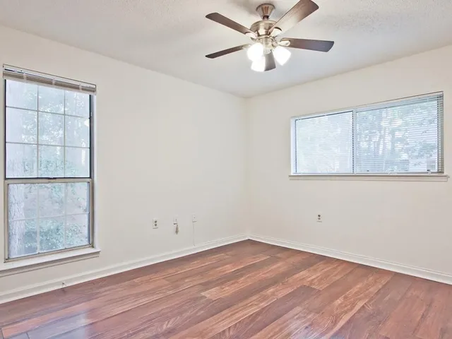 a view of empty room with wooden floor and fan