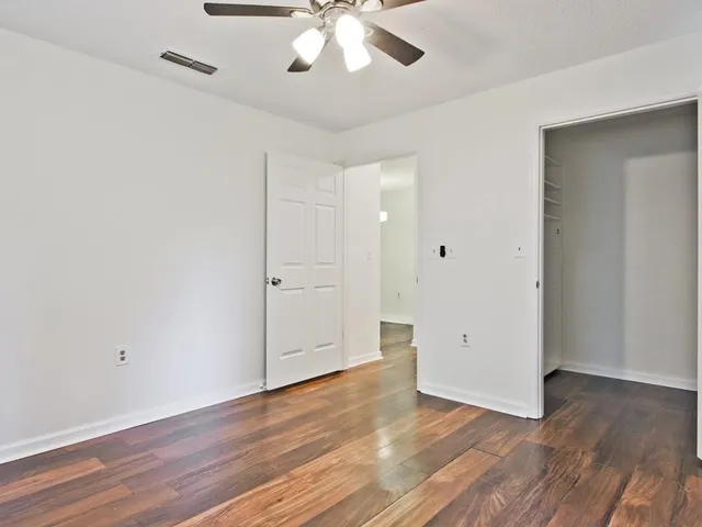 an empty room with wooden floor and ceiling fan