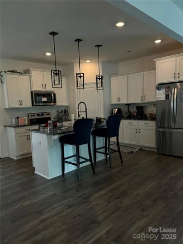 a kitchen with stainless steel appliances kitchen island granite countertop a stove top oven a sink and a refrigerator