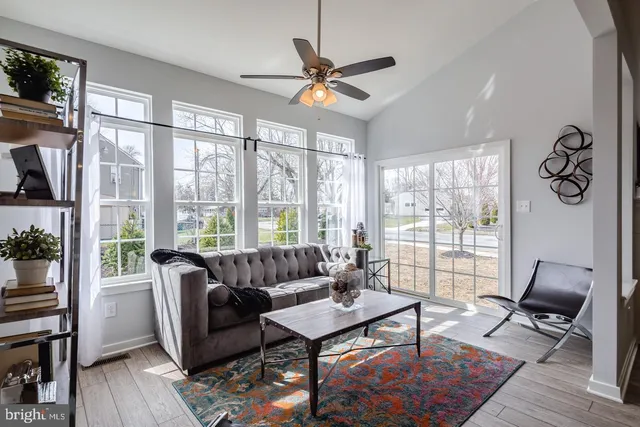 a living room with furniture a ceiling fan and a floor to ceiling window