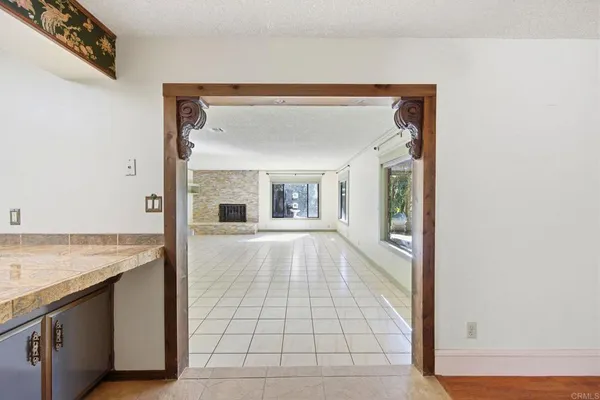 a view of an empty room with kitchen and a window