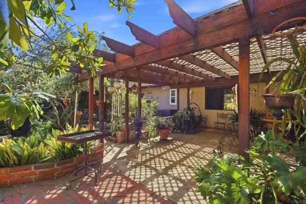 a view of a patio with table and chairs potted plants with wooden floor and fence