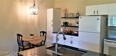 a kitchen with stainless steel appliances a refrigerator a sink a stove and white cabinets