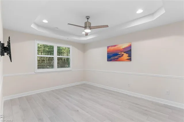 an empty room with wooden floor ceiling fan and windows