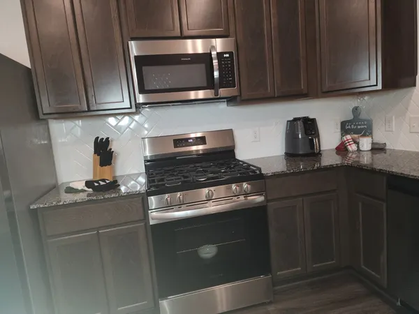 a kitchen with stainless steel appliances granite countertop wood cabinets granite counter tops and a stove top oven