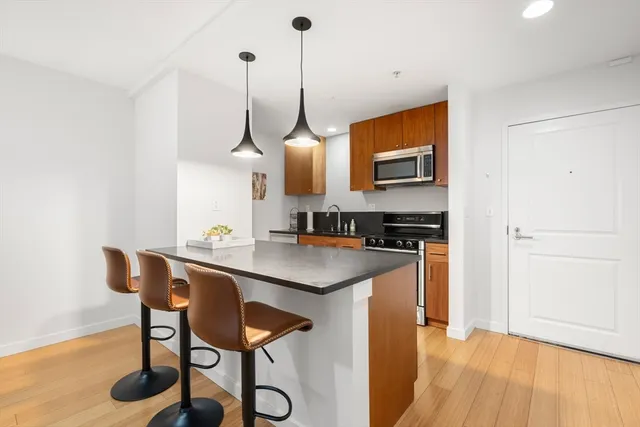 a kitchen with a sink a refrigerator a stove and chairs with wooden floor