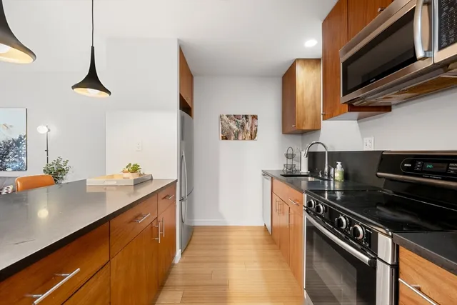 a kitchen with stainless steel appliances a sink cabinets and a wooden floor