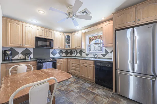 a kitchen with stainless steel appliances granite countertop a refrigerator a stove a sink a oven with a dining table and chairs