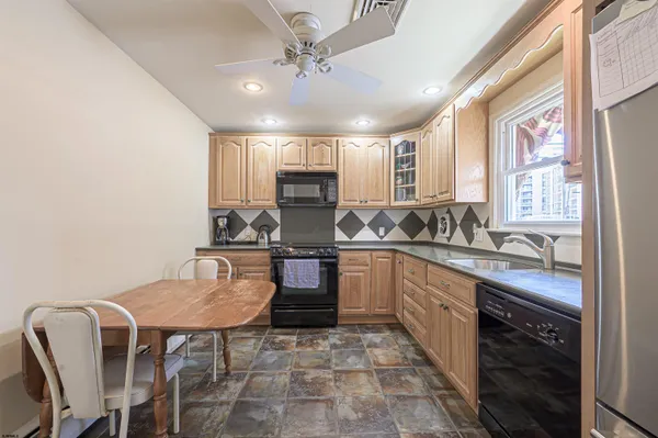 a kitchen with stainless steel appliances granite countertop a sink a stove a dining table and chairs with wooden floor