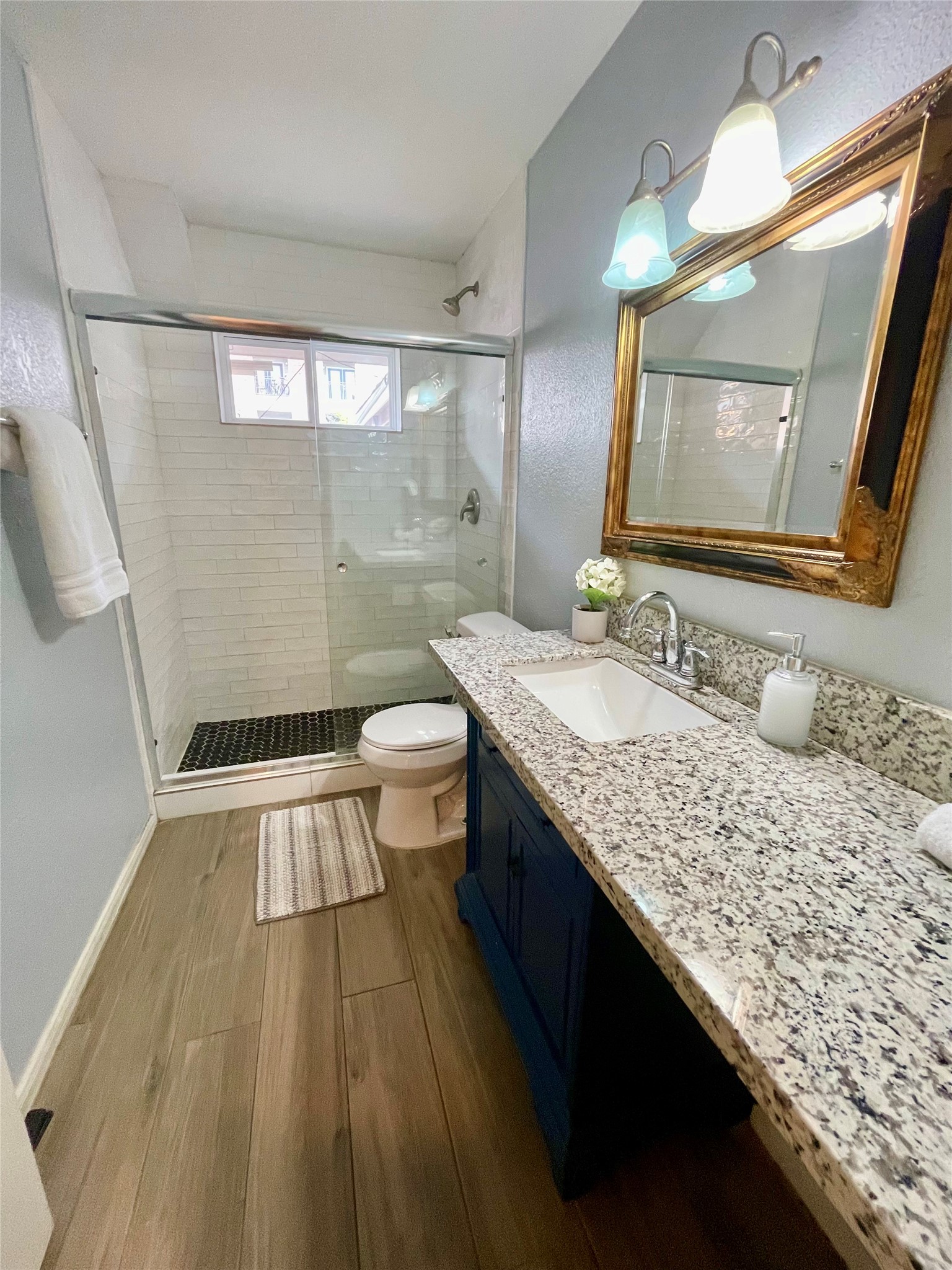 9775 Pine Lake Drive, Unit 14 Houston, TX 77055 - Photo 4 of 6 a bathroom with a granite countertop sink toilet a mirror and shower