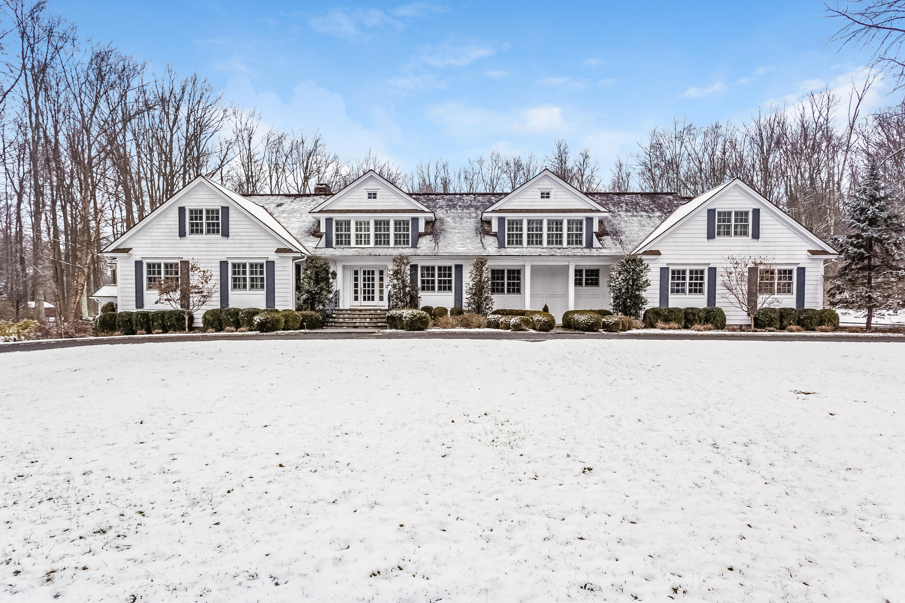 183 Turtle Back Road New Canaan, CT 06840 - Photo 1 of 53 a front view of a house with a yard covered with snow and trees