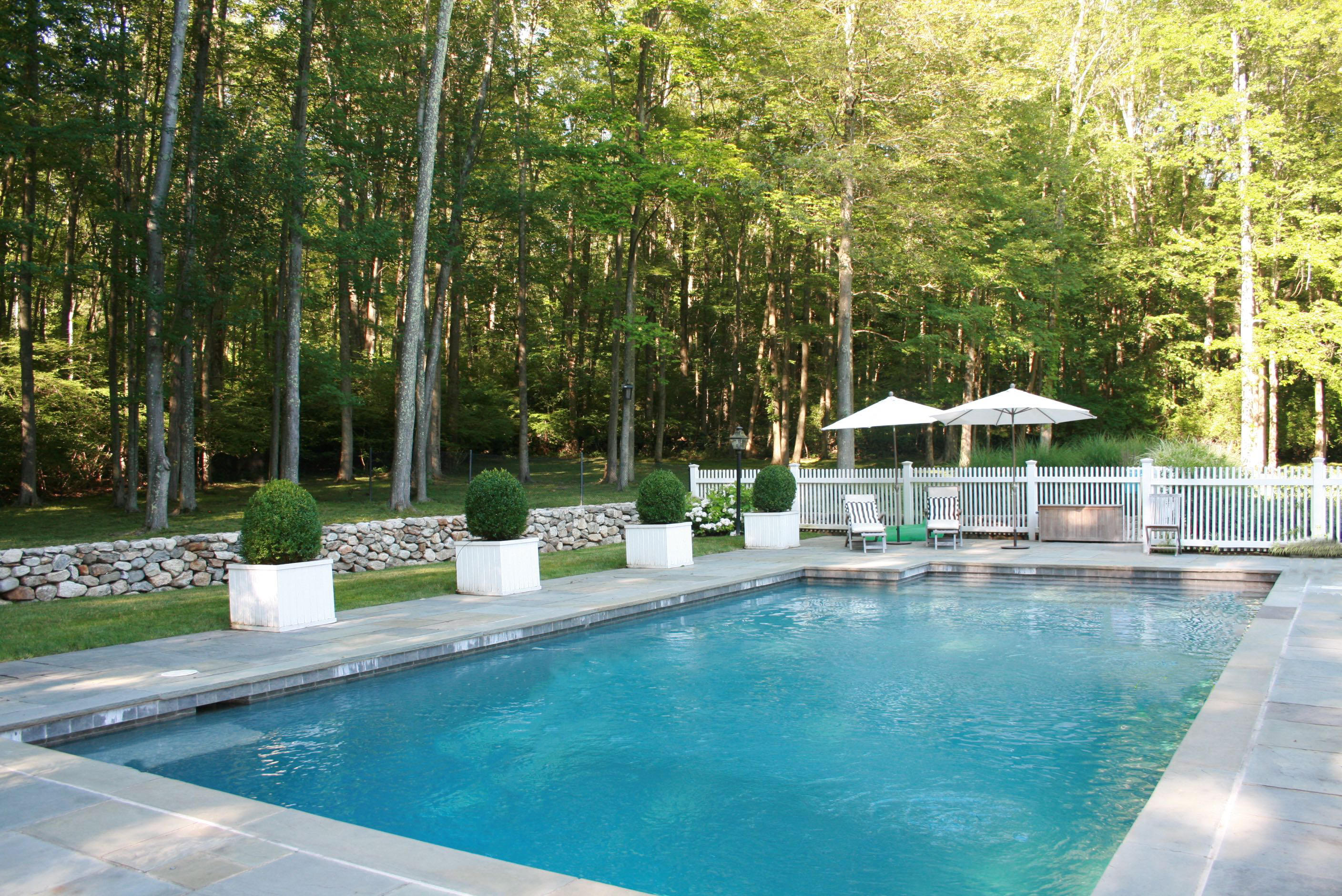 183 Turtle Back Road New Canaan, CT 06840 - Photo 4 of 53 a view of a swimming pool with a table and chairs under an umbrella