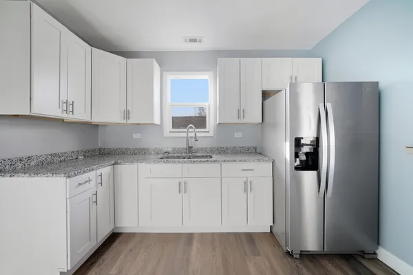 a kitchen with stainless steel appliances granite countertop a refrigerator and white cabinets