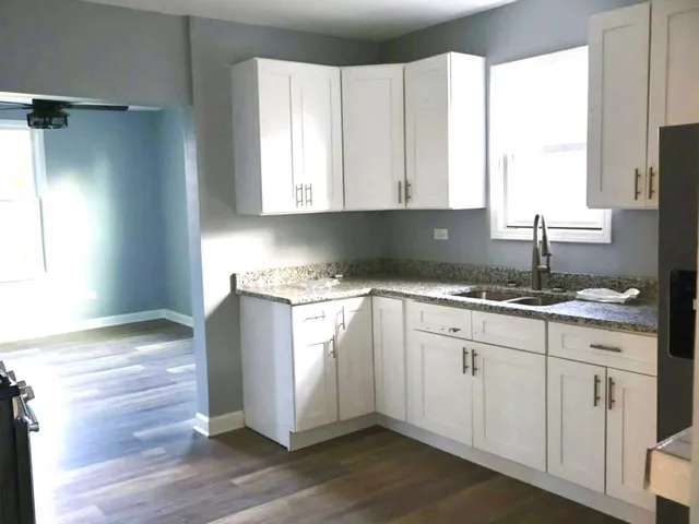 a kitchen with granite countertop white cabinets white appliances and a large window