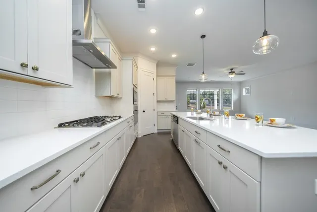 a large white kitchen with a stove and a sink