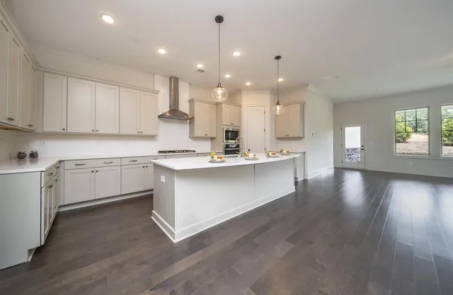 a large white kitchen with kitchen island a sink stainless steel appliances and cabinets