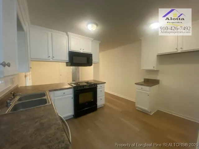 a kitchen with granite countertop a stove a sink and a microwave