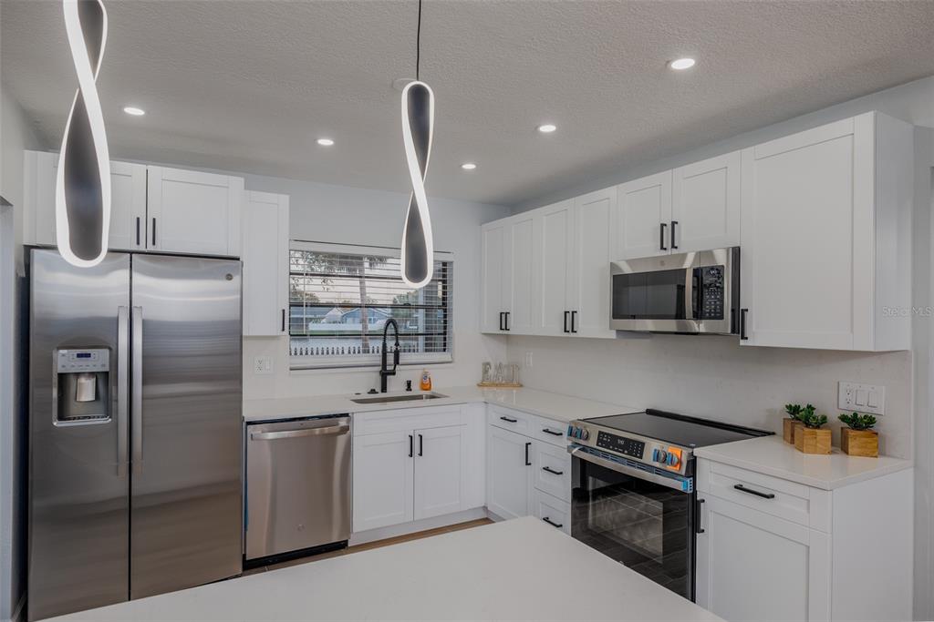 11033 Springridge Drive Tampa, FL 33624 - Photo 2 of 33 a kitchen with a sink stainless steel appliances and white cabinets