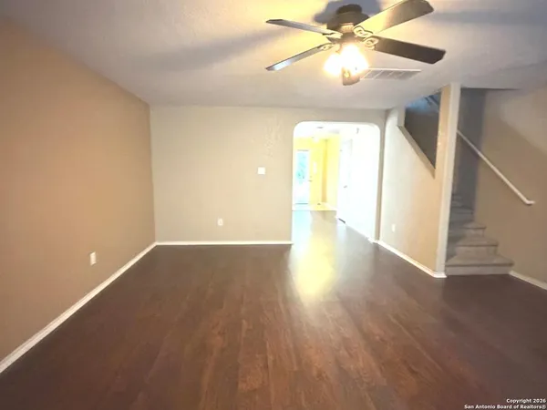 a view of an empty room with window and wooden floor