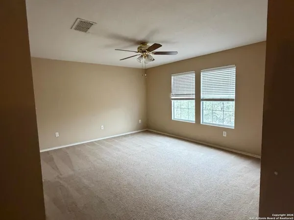 an empty room with a ceiling fan and windows