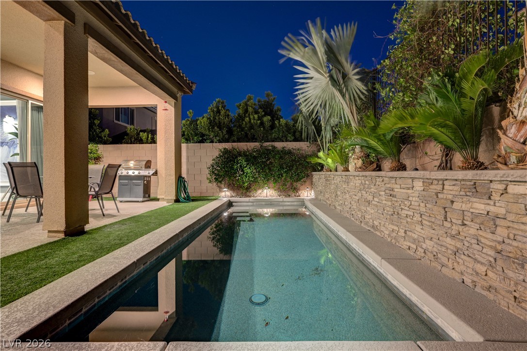 3943 Reyes Avenue Las Vegas, NV 89141 - Photo 95 of 95 A tranquil oasis awaits, with a covered patio, a sleek pool, and meticulously landscaped tropical greenery.