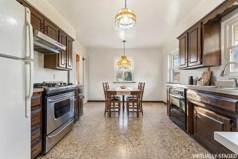 a kitchen with stainless steel appliances granite countertop a stove a sink a dining table and chairs