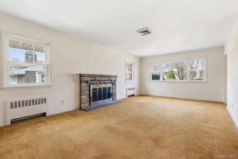 a view of an empty room with a window and fireplace