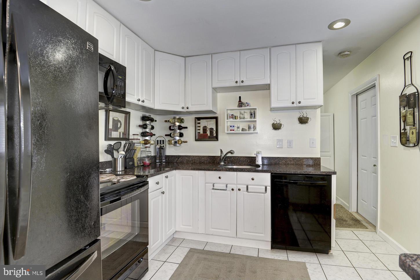 6203 Apache Street Springfield, VA 22150 - Photo 8 of 22 a kitchen with granite countertop a refrigerator oven a sink and white cabinets