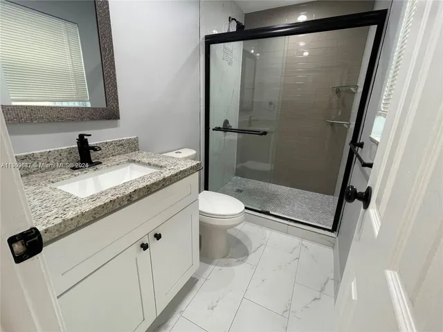 a bathroom with a granite countertop sink a toilet and shower