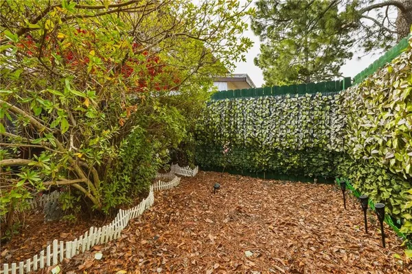 a view of a yard with plants and a brick wall