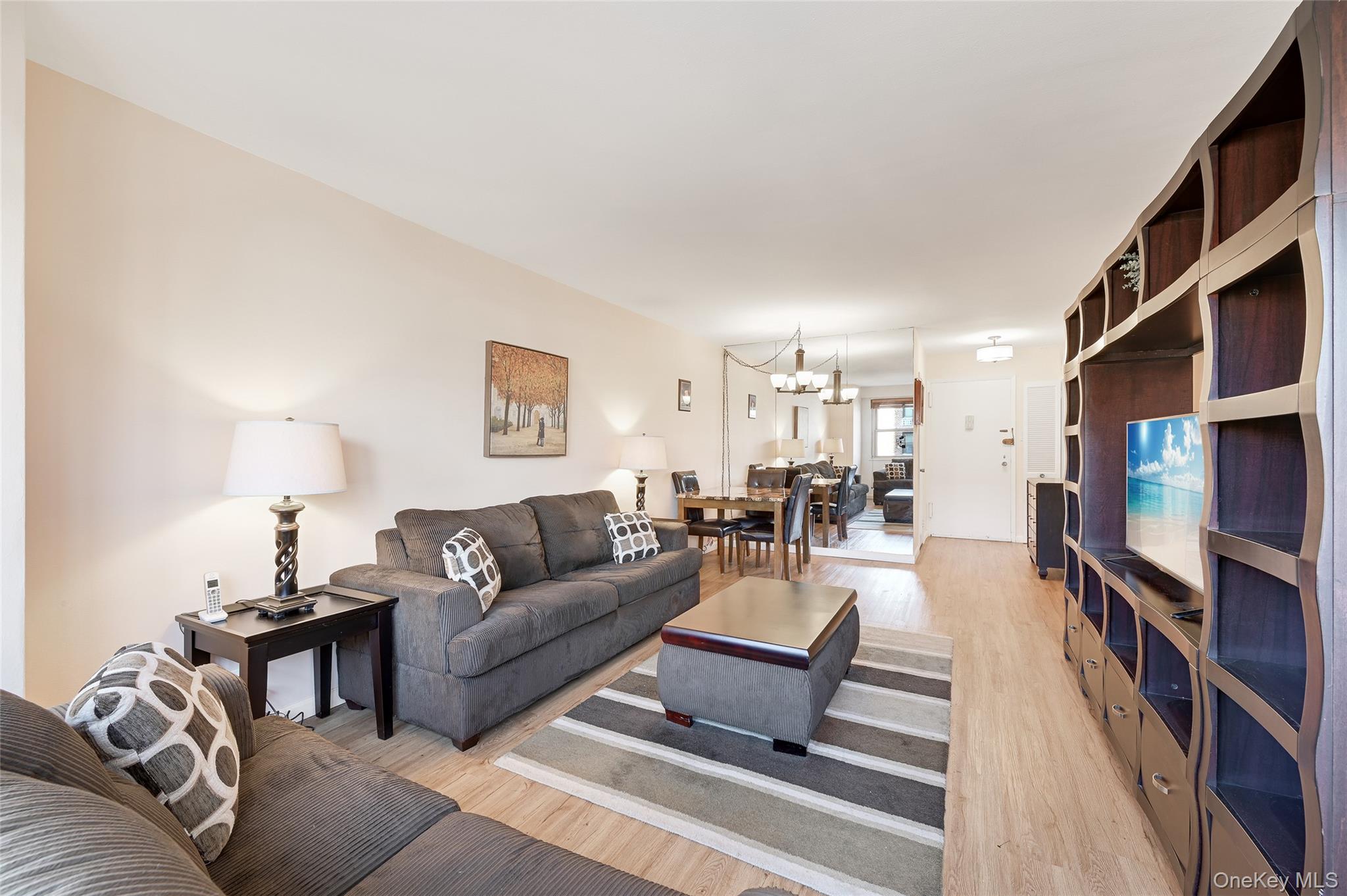 102-30 66th Road, Unit 6C Queens, NY 11375 - Photo 2 of 5 a living room with furniture and a flat screen tv