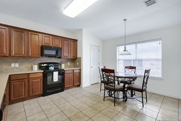 a kitchen with stainless steel appliances granite countertop a sink a stove a dining table and chairs