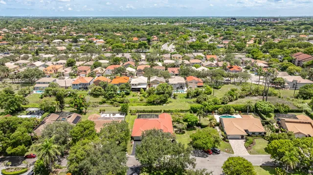 an aerial view of a residential houses with outdoor space and trees