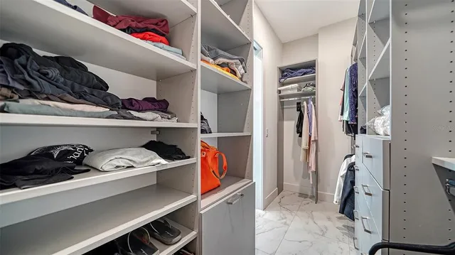 a view of walk in closet with clothes and shoes