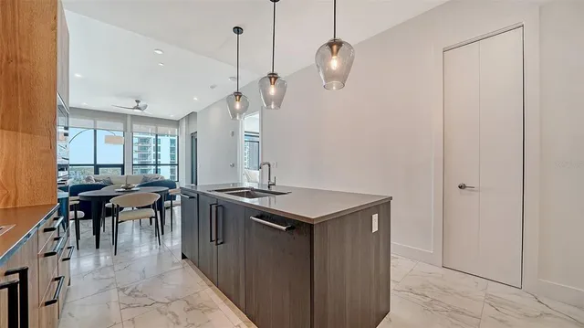 a kitchen with a stove a sink dishwasher with a dining table and chairs