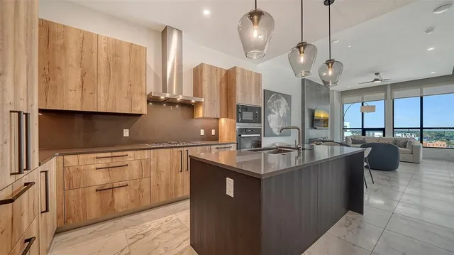 a kitchen with stainless steel appliances granite countertop a sink a oven and a large refrigerator