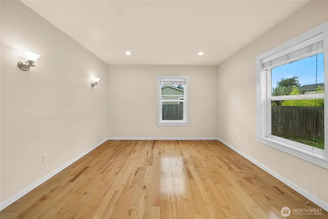 a view of empty room with wooden floor and fan