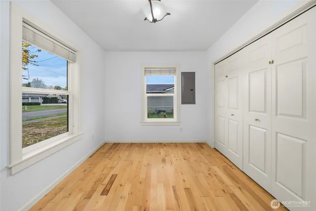 a view of empty room with wooden floor and fan