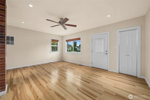 a view of empty room with wooden floor and fan