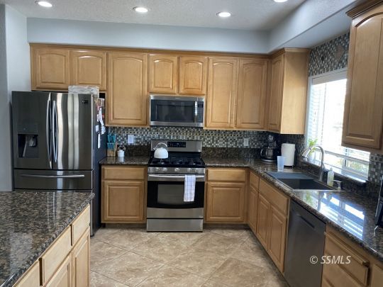 401 Acacia Street Ridgecrest, CA 93555 - Photo 5 of 42 a kitchen with stainless steel appliances granite countertop a stove a sink dishwasher a refrigerator and a microwave