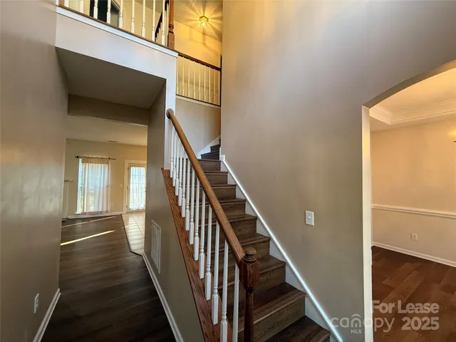 a view of a hallway with wooden floor and staircase