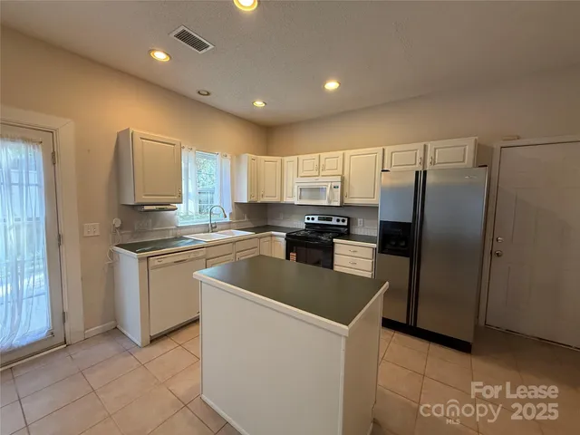 a kitchen with granite countertop a refrigerator and a stove top oven