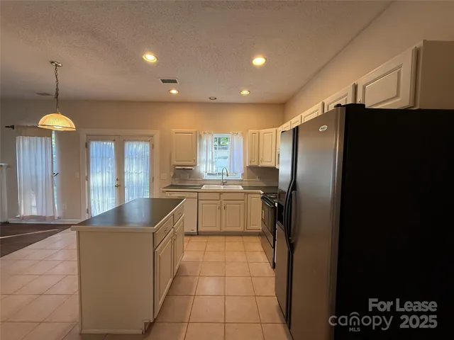 a kitchen with granite countertop a refrigerator a sink dishwasher a oven and a dining table with wooden floor