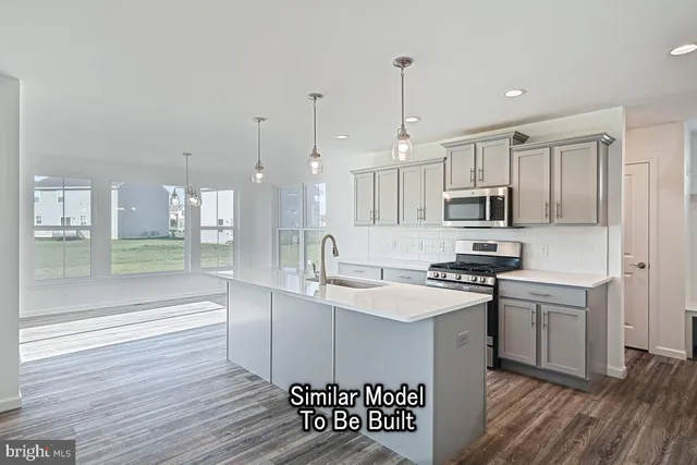 a kitchen with stainless steel appliances a sink a stove a refrigerator cabinets and wooden floor