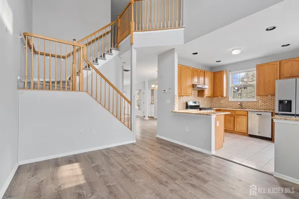 a kitchen with granite countertop a refrigerator a sink and white cabinets