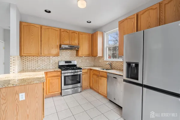a kitchen with stainless steel appliances granite countertop a refrigerator and a stove top oven